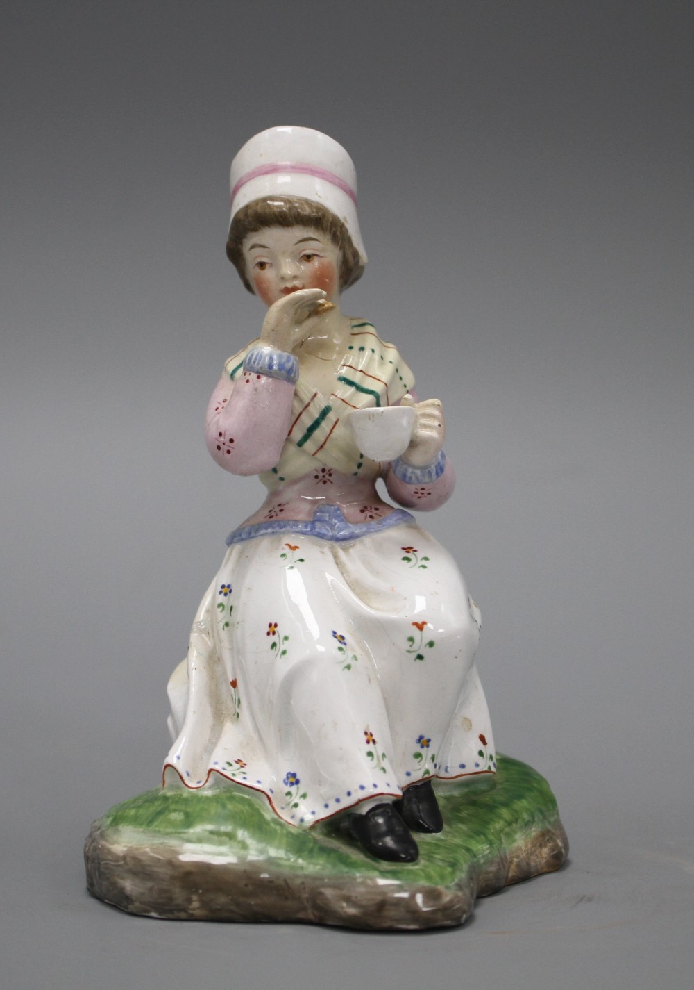 A 19th century Staffordshire figure of a seated young lady taking tea, height 13cm